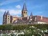 Паре-ле-Monial - Базилика Святого Сердца (романское здание) с ее квадратными башнями и восьмиугольной колокольней, выравниванием деревьев и белых роз (роз) на переднем плане