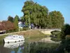 ガロンヌ運河の緑地 - ガロンヌ運河（Garonneへのサイドチャンネル）、係留ボート、花の咲く橋、木々。 Buzet-sur-Baiseにある
