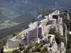 城堡Peyrepertuse - Cathar堡垒栖息在其岩石海角，在Duilhac-sous-Peyrepertuse镇，在Corbières：低矮的墙壁及其保留的旧城堡，在绿色环境中的视图