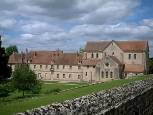 Abbaye de Noirlac - Abbaye cistercienne et parc avec des arbres, nuages dans le ciel
