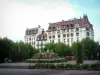 Aix-les-Bains - La Construcción y la plaza con una fuente, flores, banderas y árboles