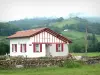 Aldudes-Tal - Haus mit roten Fensterläden und rotem Fachwerk, mit grüner Umgebung