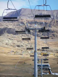 L'Alpe d'Huez - Winter and summer sports resort (ski resort): chair lift, grasslands and mountains in the background, in autumn