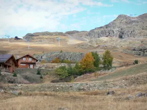 L'Alpe d'Huez - Chalets, ski lift of the winter and summer sports resort (ski resort), grasses and trees with autumn colors