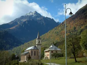 Alps landscapes in the Savoie - Lamppost, church and houses of a village, a forest in autumn, mountain and clouds in the sky