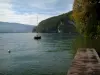 Annecy lake - Wooden pontoon, lake, sailboat, trees and hills covered with forests