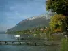Annecy lake - Lake, wooden pontoons, boats, shore, trees with autumn colours, houses, forest and mountain