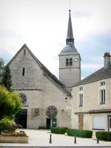 Arc-en-Barrois - El campanario y la fachada de la iglesia de Saint-Martin, casa de piedra y decoración floral