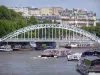 Banks of the Seine river - Debilly footbridge, moored barges and cruise boat sailing on the Seine river