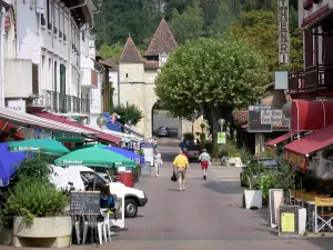 Barbotan-les-Thermes - Thermalbad (auf der Gemeinde Cazaubon): Avenue des Thermes, mit ihren Häusern und ihren Einkaufsläden, und Glockenturm-Vorbau (ehemaliges befestigtes Tor) der Kirche Saint-Pierre im Hintergrund