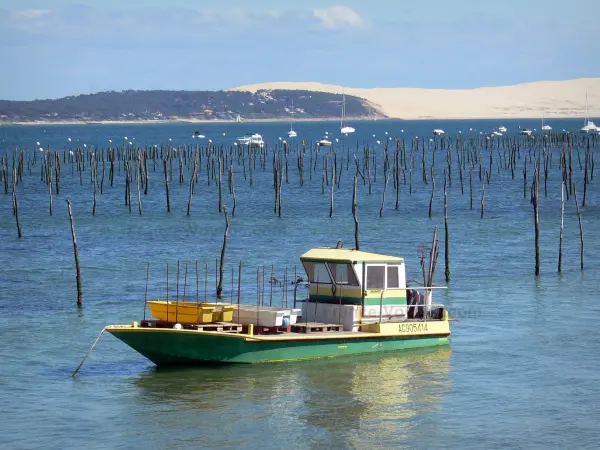 Bassin d'Arcachon - Bateau d'ostréiculteur sur les eaux du bassin d'Arcachon avec vue sur la dune du Pilat