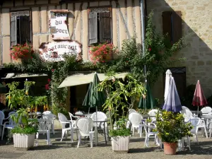 Bassoues - Cafetería con terraza y la casa de entramado de madera decorado con flores