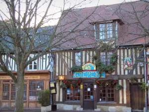 Beuvron-en-Auge - Tree, half-timbered houses, creperie, and shop of the central square in the Pays d'Auge area