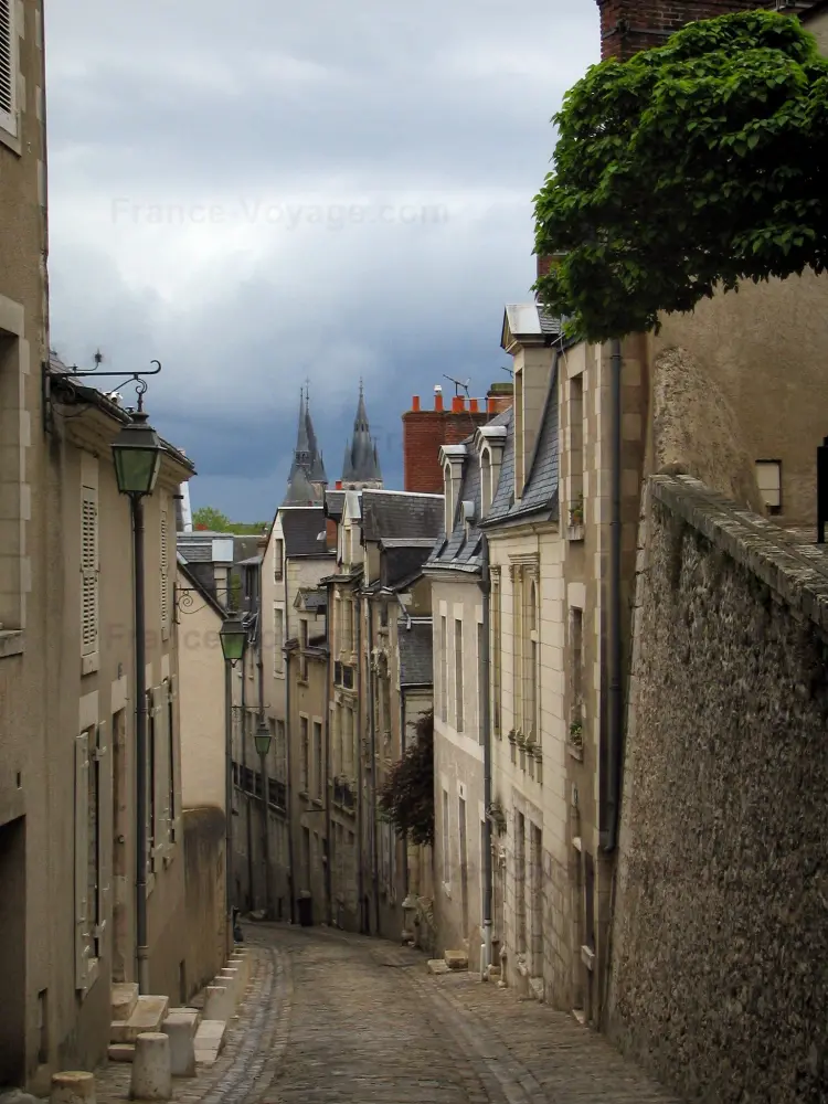 Blois - Ruelle en pente bordée de maisons, lampadaires et ciel orageux