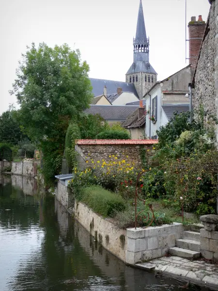 Bonneval - Église Notre-Dame de style gothique et sa flèche, jardin fleuri et maisons du village au bord de la rivière Loir (fossé en eau) ; dans la Beauce