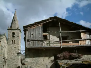 Bonneval-sur-Arc - Altes Haus aus Stein mit seinem Holzbalkon, Glockenturm der Kirche des savoyard Dorfes,  bewölkter Himmel, in der Haute-Maurienne (Nationalpark Vanoise)