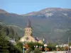 La Bourboule - Station thermale : clocher de l'église Saint-Joseph, maisons, lampadaires fleuris, arbres, forêt et montagne ; dans le Parc Naturel Régional des Volcans d'Auvergne, dans le massif des monts Dore
