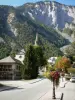 Le Bourg-d'Oisans - Clocher de l'église Saint-Laurent, maisons, rue et lampadaires fleuris du village, montagne surplombant l'ensemble