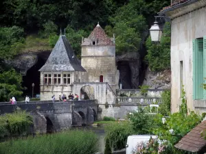 Brantôme - Facciata di una casa in primo piano con vista sul ponte che attraversa il fiume Coudé (Dronne), il padiglione rinascimentale e la torre di San Rocco, in Périgord Verde