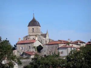 Brigueuil - Romanische, befestigte Kirche Saint-Martial mit ihrem Kirchturm, Häuser des Dorfes und Bäume