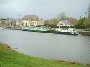 Canal from Nantes to Brest - Bank in foreground, canal (river), moored barges and houses in Blain