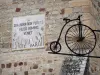 La Canourgue - Zonnewijzer met Latijnse inscriptie op de kerktoren, en smeedijzeren teken de vorm van fiets