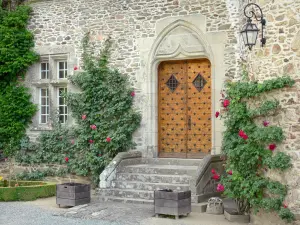 Castello di Pompadour - Porta e la facciata del castello decorato con rose rampicanti in fiore