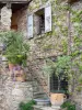 Castelnou - Façade d'une maison en pierre et ses arbustes en pots