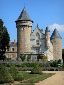 Castillo de Busset - Torres y el edificio principal del castillo que domina los arbustos podados del jardín a la francesa