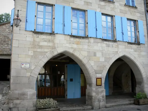 Caylus - Arcaded stone house with blue shutters of the Place de la Mairie square