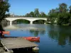 Charente valley - Bridge spanning the Charente river, trees along the water, pontoon, canoes, Saint-Simeux church overhanging the set