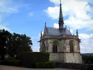 Château d'Amboise - Saint-Hubert chapel of Flamboyant Gothic style, trees and hedges, clouds in the sky