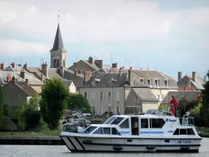 Châtillon-en-Bazois - Jacht fahrend auf dem Nivernais-Kanal, Kirchturm der Dorfkirche Saint-Jean-Baptiste und Häuser des Dorfes