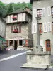 Chaudes-Aigues - Kreuz, Fassaden blumengeschmückter Häuser und Geschäfte der Kurstadt