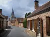 Chaumont-sur-Tharonne - Campanario de la Iglesia, calle llena de casas de ladrillo y cielo tormentoso, en Sologne