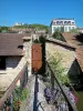 Chevreuse - Kleine Blumenbrücke überspannt den Kanal mit Blick auf die Häuser des Dorfes und das Château de la Madeleine