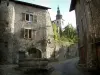 Ciudad medieval de Conflans - San Gabriel-Pérouse fuente decorada con flores, casas, alférez de hierro forjado y el campanario de la iglesia de San Grat