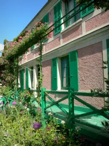 Claude Monet’s house and gardens - Monet's pink house with green shutters and its surroundings with flowers; in Giverny