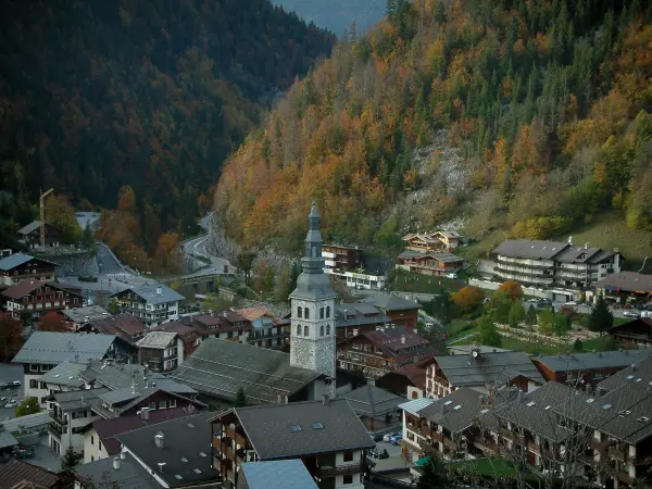 La Clusaz - Vista aérea de la iglesia y las casas (cabañas) de la localidad (estación de esquí y en verano), las montañas cubiertas de árboles en los colores del otoño