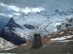 Col de l'Iseran - Parc National de la Vanoise : pelouse alpine avec de la neige, montagne enneigée et ciel nuageux (route des Grandes Alpes)