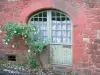 Collonges-la-Rouge - French window of a red sandstone stone house decorated with a rose in bloom