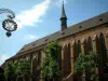 Colmar - Forged iron shop sign, trees and Dominicans church