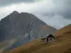 Les cols de la route des Grandes Alpes - Paysages alpins de Savoie: Bergerie (maisonnette) en pierre, alpage, montagne dénudée et ciel nuageux (route des Grandes Alpes)