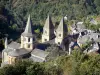 Conques - Vue sur les tours de l'église abbatiale Sainte-Foy et les toits de lauzes du village, dans un cadre de verdure