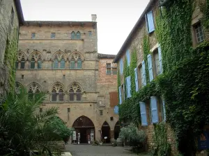 Cordes-sur-Ciel - Place Saint-Michel, maison du Grand Veneur de style gothique et demeure en pierre recouverte de lierre avec des volets bleus