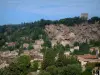 Cotignac - Arbres, maisons du village, ruines du château (tour) et falaise de tuf trouée de grottes