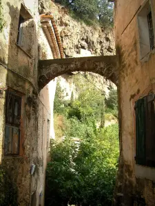 Cotignac - Houses of the village with view of the tuff cliff pierced by caves