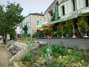 Coulon - Macizos de flores, restaurante con terraza y fachadas de casas de la aldea