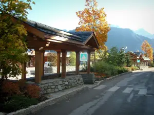 Courchevel - Street of the ski resort (winter sports) with a wooden shelter, shrubs and trees in autumn