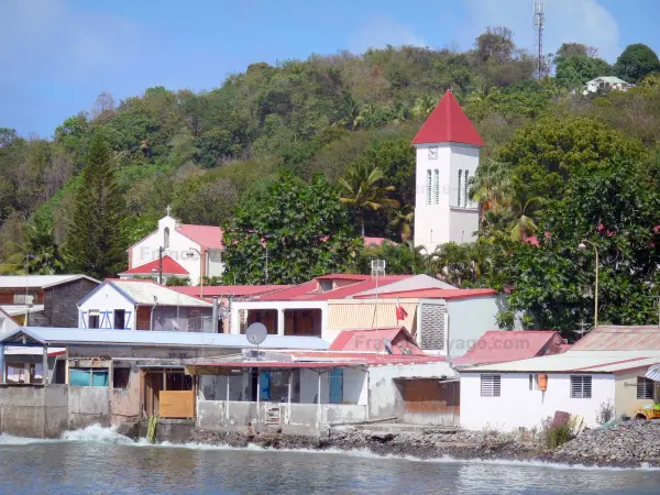 Deshaies - Klokkentoren van de kerk van St. Peter en St. Paul en de huizen van het dorp aan de Caribische Zee ; op het eiland Basse - Terre